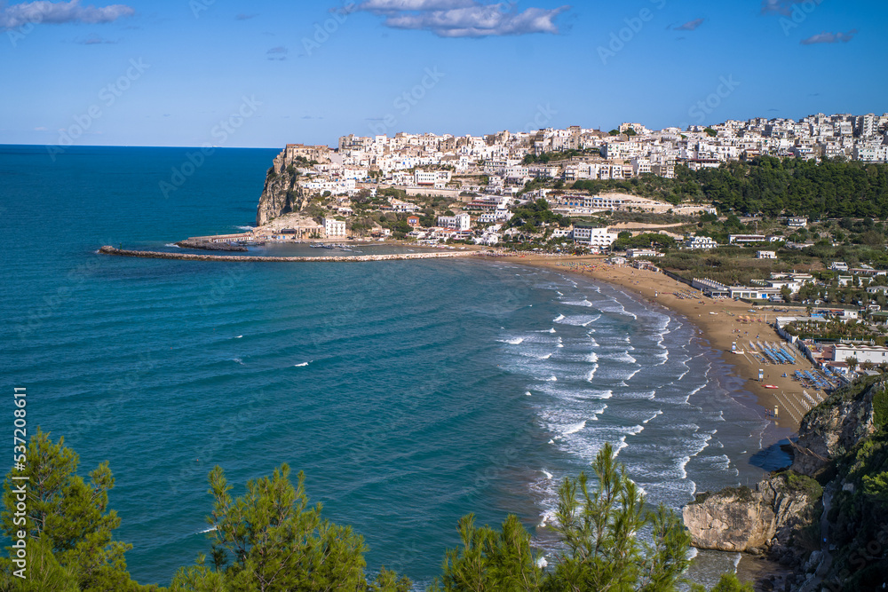 white houses on a hill by the Adriatic Sea in Italy. Historical village buildings in Italy view from the sea on a clear day. Italian coast with a small town on a hill