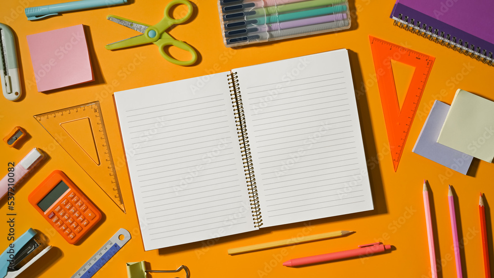 Blank notepad surrounded by various school supplies on yellow background. Flat lay, Top view Blank notepad surrounded by various school supplies on yellow background. Flat lay, Top view
