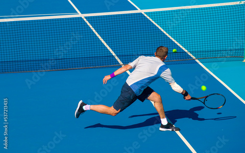 Tennis player playing tennis on a hard court on a bright sunny day © Павел Мещеряков
