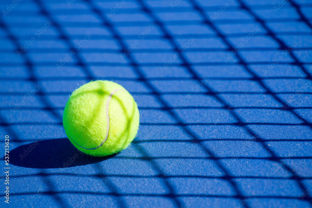 a tennis ball lies on a blue hard court