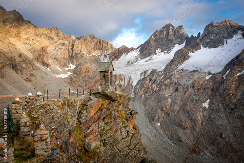 Old stone bell tower high Alps mountains cliff glacier, Refuge Marinelli Bombardieri , Bernina range mountaineering tourism, Italy travel Europe.