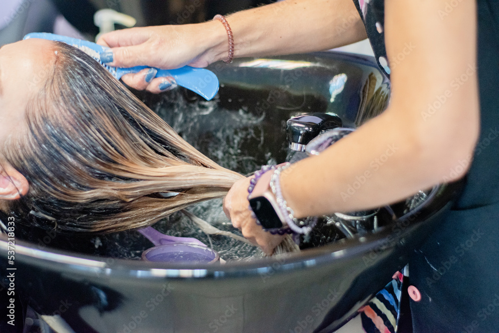 Hairdresser washing the hair of a woman lying on the hairdresser's sink