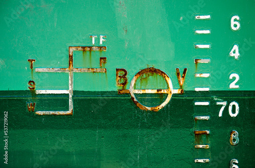 Draught marks on the steel hull of a ship, painted light and dark green photo