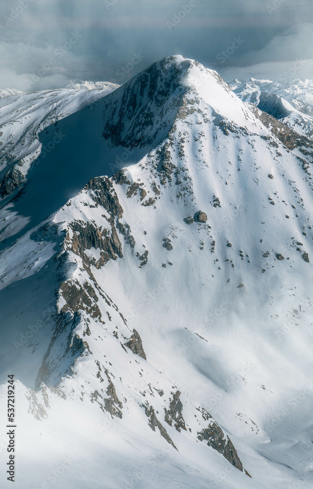 Beautiful high snowy mountain peak from above in the Austrian alps during a sunny afternoon.