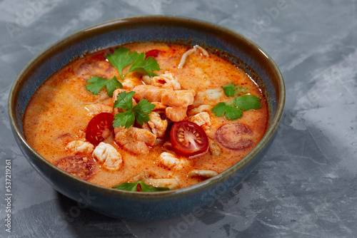 Traditional Thai food cuisine. Tom Yum spicy soup in black bowl on grey background. Thai food concept. Top view