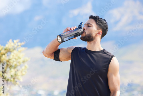 Fitness, blue sky and man drinking water from bottle to refresh and relax after workout, running or sports training. Cardio runner, exercise and thirsty young person with liquid drink for hydration