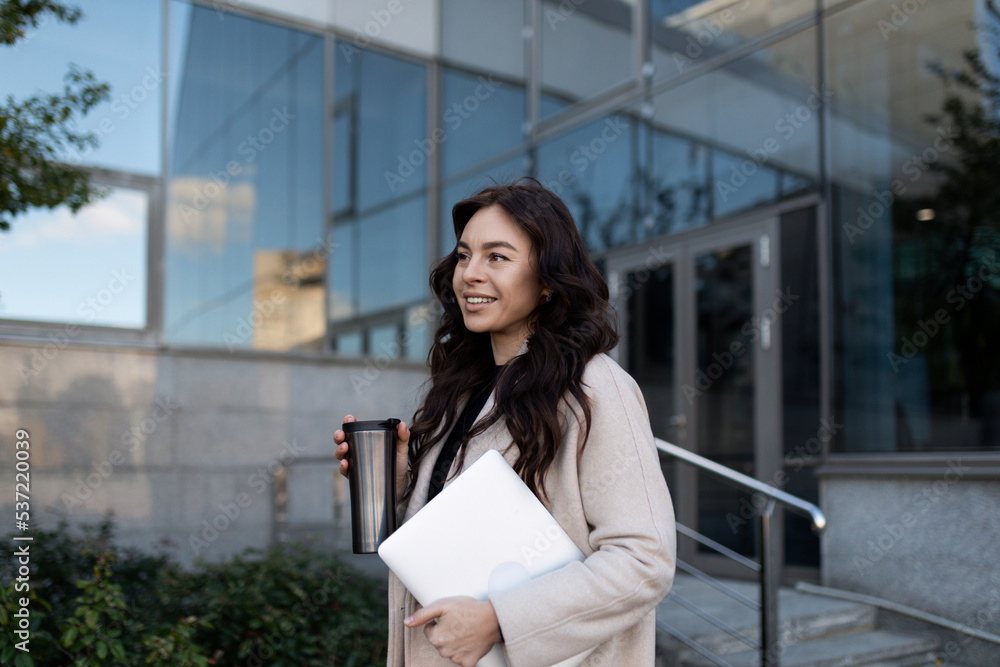 confident modern businesswoman goes to work with a big smile with a laptop in her hands confident modern businesswoman goes to work with a big smile with a laptop in her hands