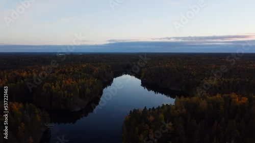 Reverse ascending over a glass like lake sourounded by verdant autumn forest photo