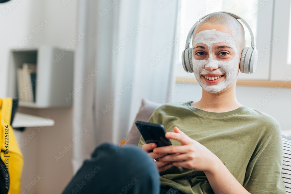 teenager shave head female sit in her room and using smart phone teenager shave head female sit in her room and using smart phone