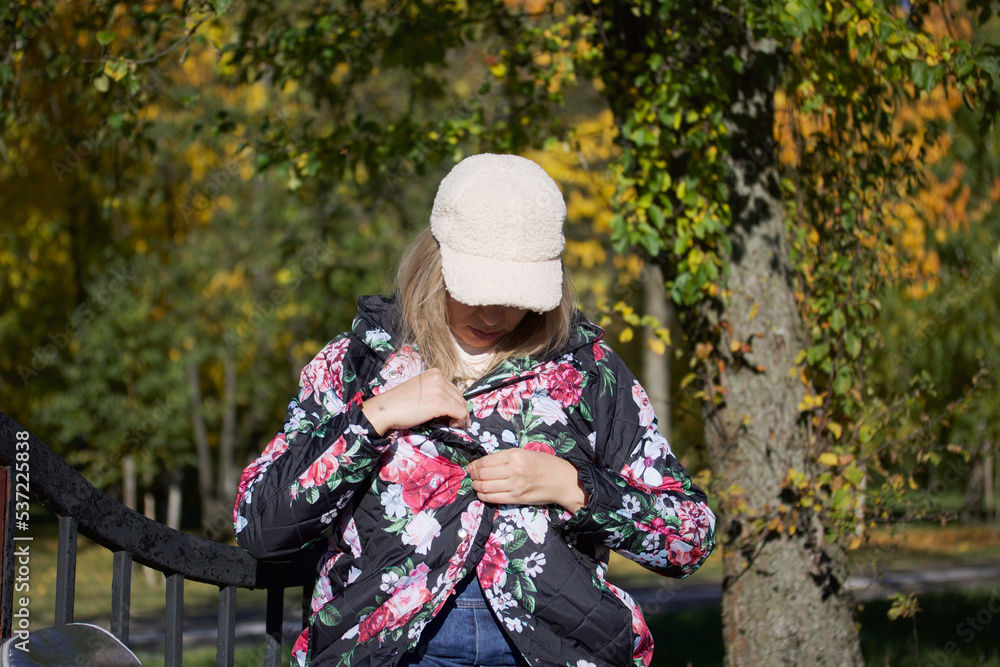 The girl is sitting on a park bench. Dressed in autumn clothes. Autumn city park. The girl is sitting on a park bench. Dressed in autumn clothes. Autumn city park.