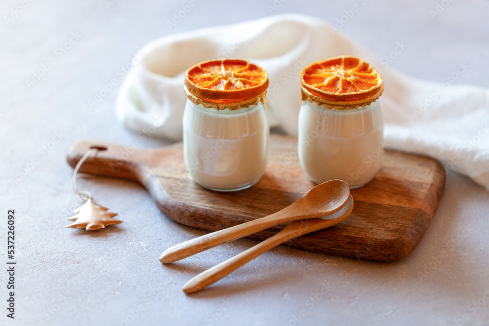 Fototapeta premium Two portions of joghurt decorated with dry orange slices, winter breakfast
