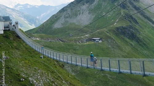 Suspension bridge in Gastein, Stubnerkogel, Austria. Man with his son walking, crossing the abyss. Tourist travelers spot in Alms mountains. Landscape panoramic view on sunny summer day (ID: 537228092)