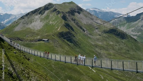 Suspension bridge in Gastein, Stubnerkogel, Austria. Tourists on the top of mountains and hills, abyss. Travel crowd people walking crossing, sightseeing, hiking long construction. Beautiful nature. (ID: 537228212)