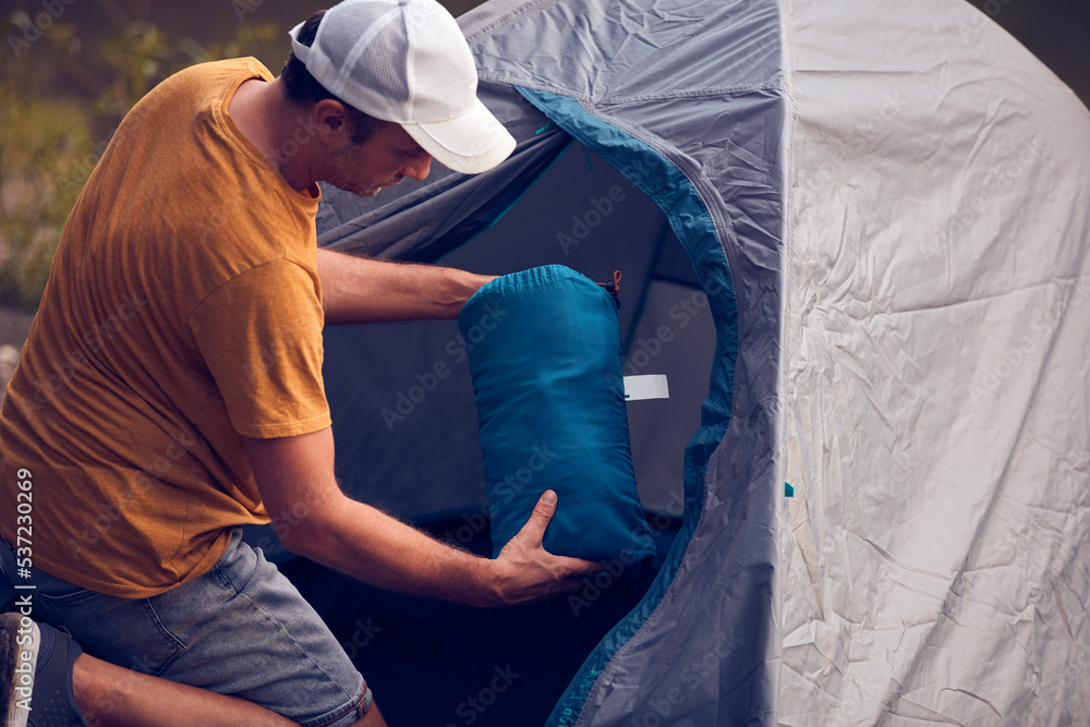 Man camping in nature, setting up the tent for overnight staying near forest river. Man camping in nature, setting up the tent for overnight staying near forest river.