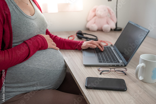 Canvas Print Cropped image of beautiful pregnant business woman typing with one hand holding other hand on her belly while finishing working from home