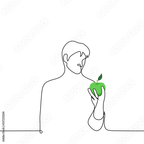 male looks at the green apple he holds in his hand - one line drawing vector. concept transition to a diet, love or dislike for apples