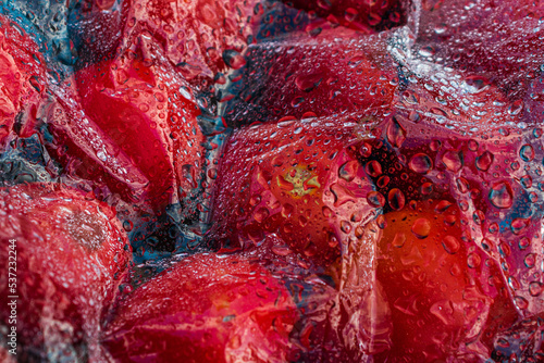 Textured background of freshly picked tomatoes under glass or film with water drops
