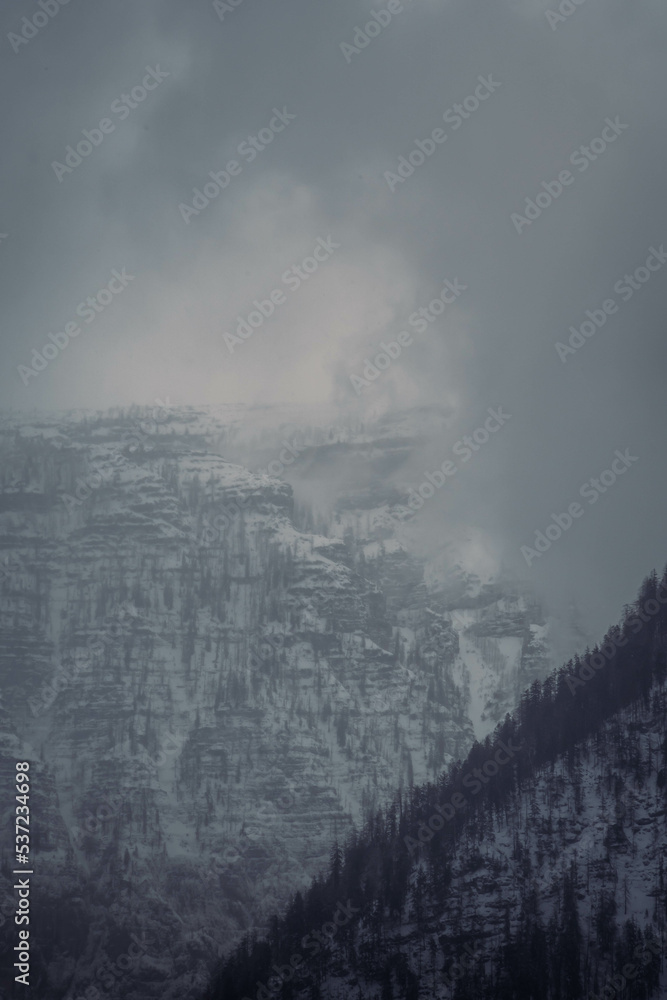 Mountain range with strong atmosphere during a snowy, dark winter afternoon