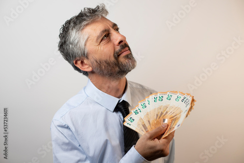 riche homme d'affaires de 50 ans qui joue avec une liasse de billets de banque. Concept du profit, du capitalisme et de l'enrichissement photo