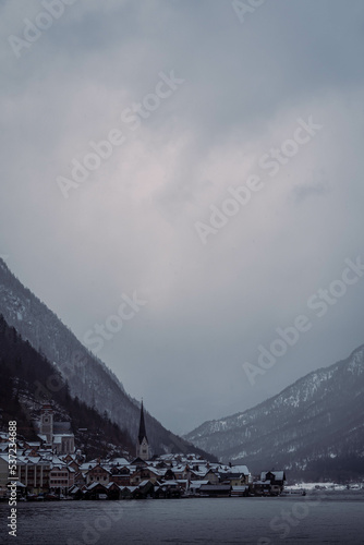 Typical alpine style buildings in the distance over the lake in Hallstatt, Austria during a snowy winter afternoon.