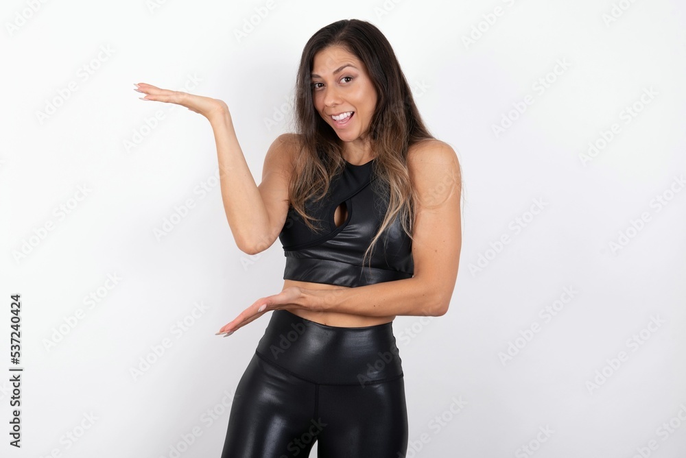 Obraz premium young beautiful woman wearing sportswear over white background pointing aside with both hands showing something strange and saying: I don't know what is this. Advertisement concept.