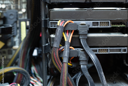 Very dirty wires with connectors are connected to the computer hard drive. HDD and SSD disc. Old colored wires in braided wrapper. Stranded electrical wire in electronic equipment. Electronics repair