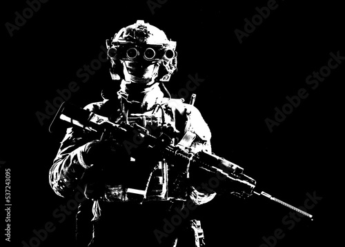 Modern army special forces equipped soldier  anti terrorist squad fighter  elite mercenary armed assault rifle  standing in darkness with night vision goggles on helmet  studio portrait