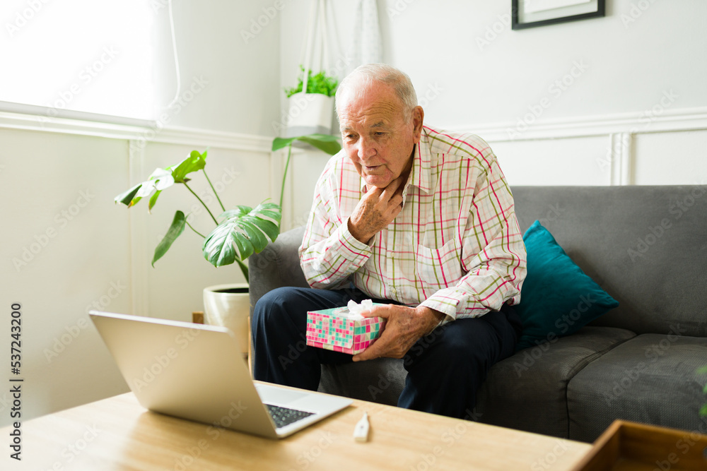 Ill elderly man with the flu talking with a virtual doctor on a video call Ill elderly man with the flu talking with a virtual doctor on a video call