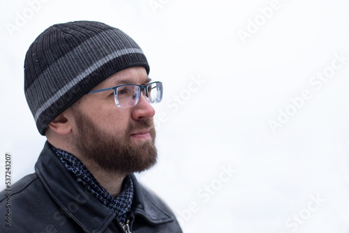 Portrait of adult thinking serious man with beard and glasses in warm winter clothes black color on the white background © Оксана Рязанова