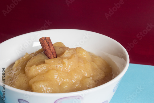 A cinnamon stick on applesauce on a blue and red background. Healthy food.