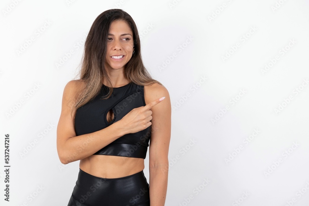 young beautiful woman wearing sportswear over white background Pointing aside worried and nervous with forefinger, concern and surprise concept. young beautiful woman wearing sportswear over white background Pointing aside worried and nervous with forefinger, concern and surprise concept.