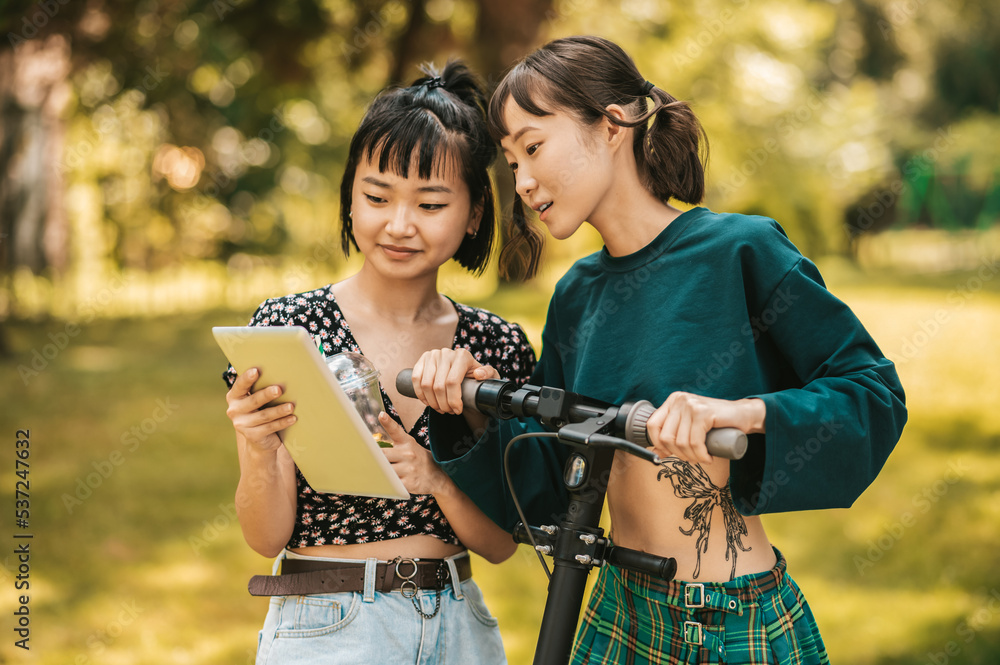 Girls in the park watching something online and looking interested Girls in the park watching something online and looking interested