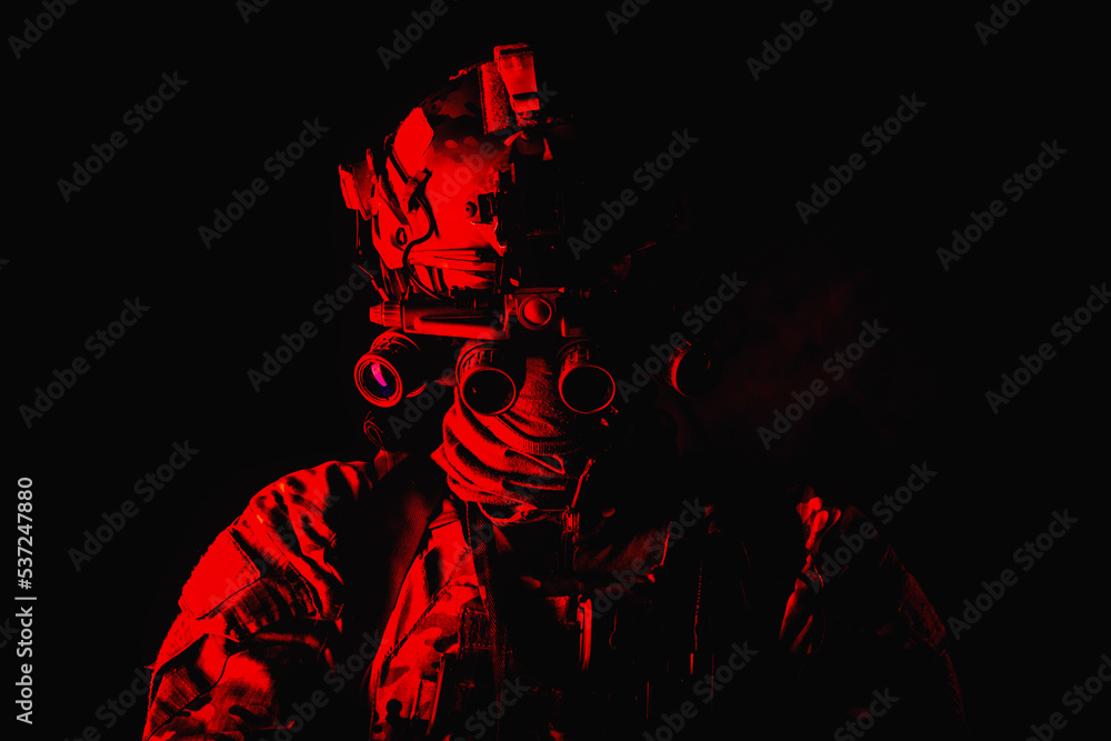 Half length, low key studio shoot of army soldier, marine infantryman in mask, camo uniform, equipped modern ammunition, armed service rifle standing in darkness with night vision device on helmet Half length, low key studio shoot of army soldier, marine infantryman in mask, camo uniform, equipped modern ammunition, armed service rifle standing in darkness with night vision device on helmet