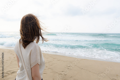 The back view of woman staring the horizon over the ocean 海に広がる地平線を見つめる女性の後ろ姿