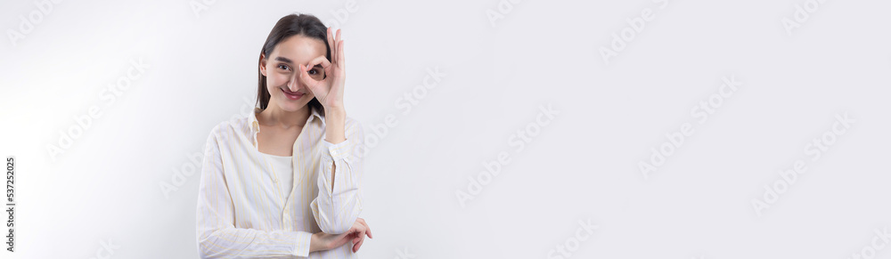 Close up portrait of attractive quirky young woman making binoculars with hands showing ok gesture on white studio background. Close up portrait of attractive quirky young woman making binoculars with hands showing ok gesture on white studio background.