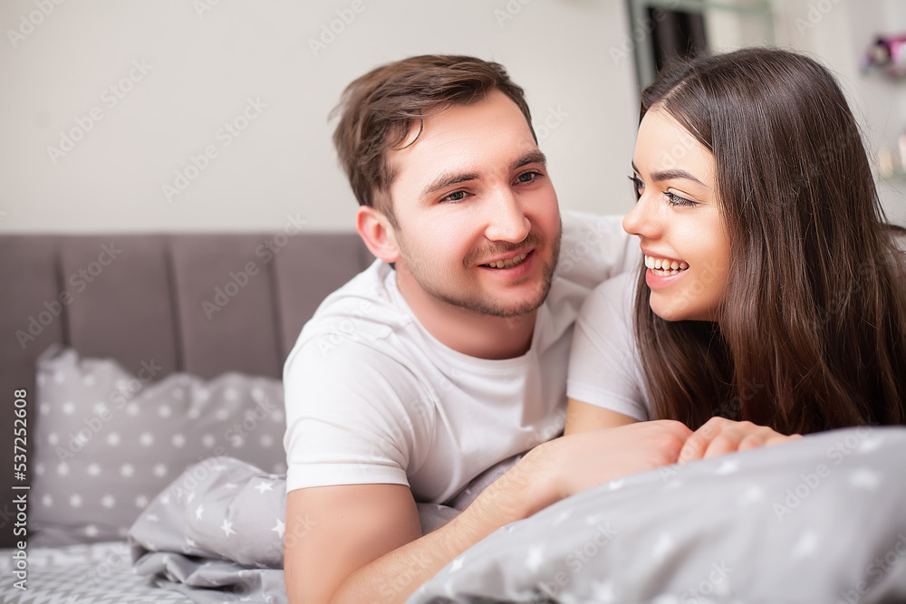 Happy sensual young couple lying in bed together Happy sensual young couple lying in bed together