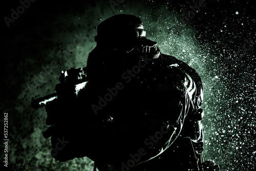 Commando fighter, professional mercenary, special forces soldier with camouflaged face, loaded with ammunition, armed assault rifle, patrolling on secret mission, sneaking in darkness ready to fight