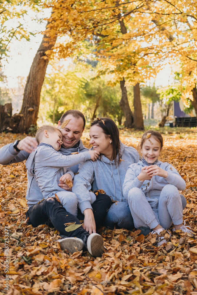 Fototapeta premium Loving mother and father spending leisure time at park with their kids. Family time means the absolute world to us. Sunny day, good mood