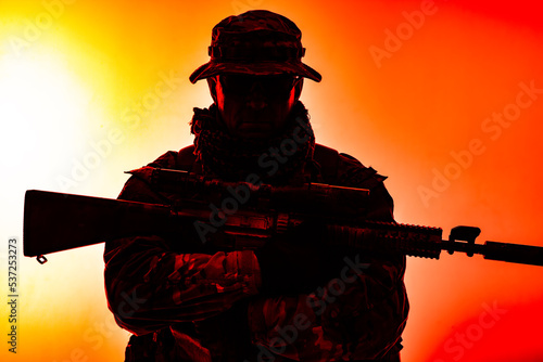 Army special forces soldier, commando shooter, mercenary in camouflage uniform, bonnie, hidden behind mask and glasses face, armed service rifle, low key, isolated studio shoot photo