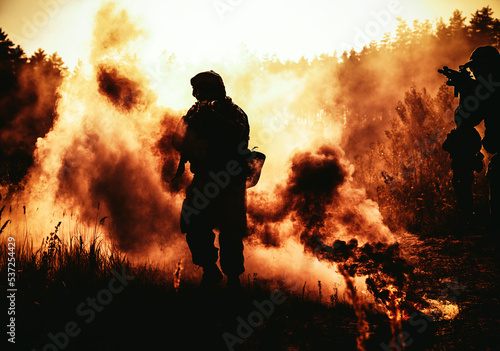 United States Marines in action. Military action, desert battlefield, smoke grenades., fire and explosions. Sun setting, dark silhouette in the desert