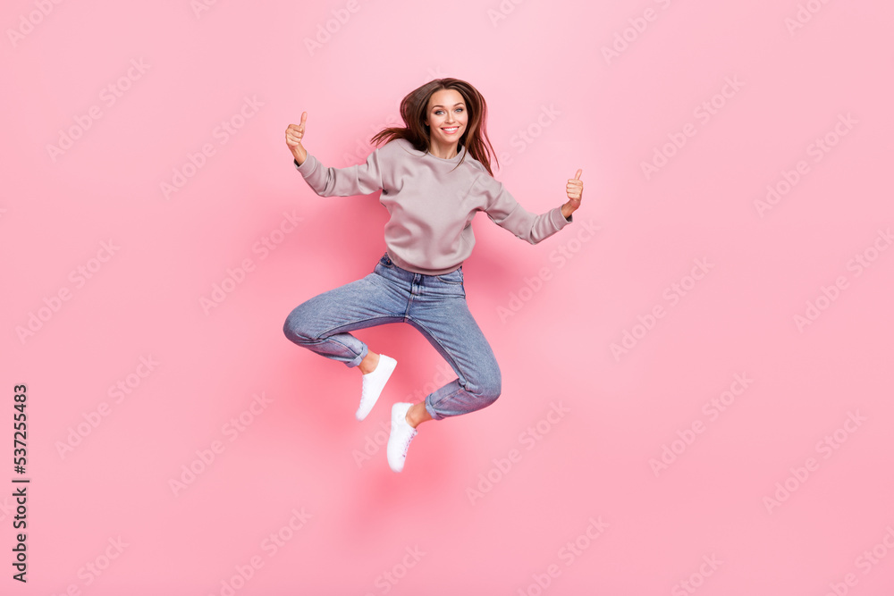 Full length portrait of excited carefree person jumping hands fingers demonstrate thumb up isolated on pink color background