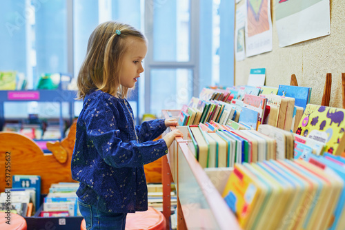 4 year old girl selecting a book in municipal library photo