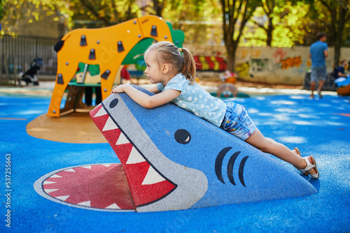Adorable preschooler girl playing with giant shark on a playground © Ekaterina Pokrovsky