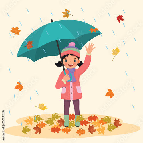 happy little girl holding umbrella under rain with fallen leaves in autumn 