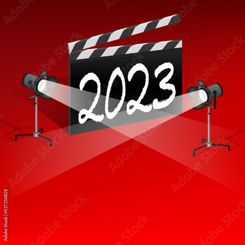 Un clap de cinéma sur un fond rouge avec l’inscription 2023. Il est éclairé par deux projecteurs pour présenter les différents événements cinématographique de la nouvelle année.