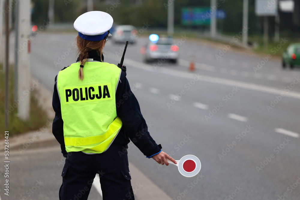 Policjantka z lizakiem do zatrzymywania pojazdów kontroluje ruch drogowy.  - obrazy, fototapety, plakaty 