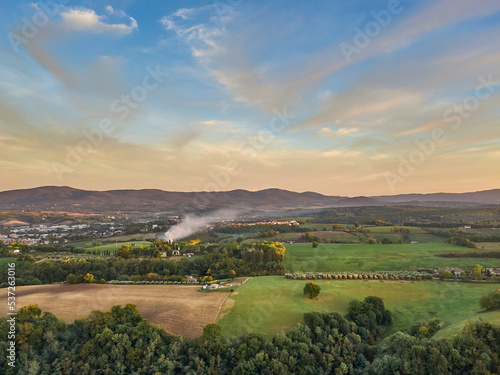 An aerial landscape view of Tuscany's countryside at sunset.