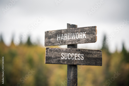 vintage and rustic wooden signpost with the weathered text quote hardwork success, outdoors in nature. blurred out forest fall colors in the background. photo