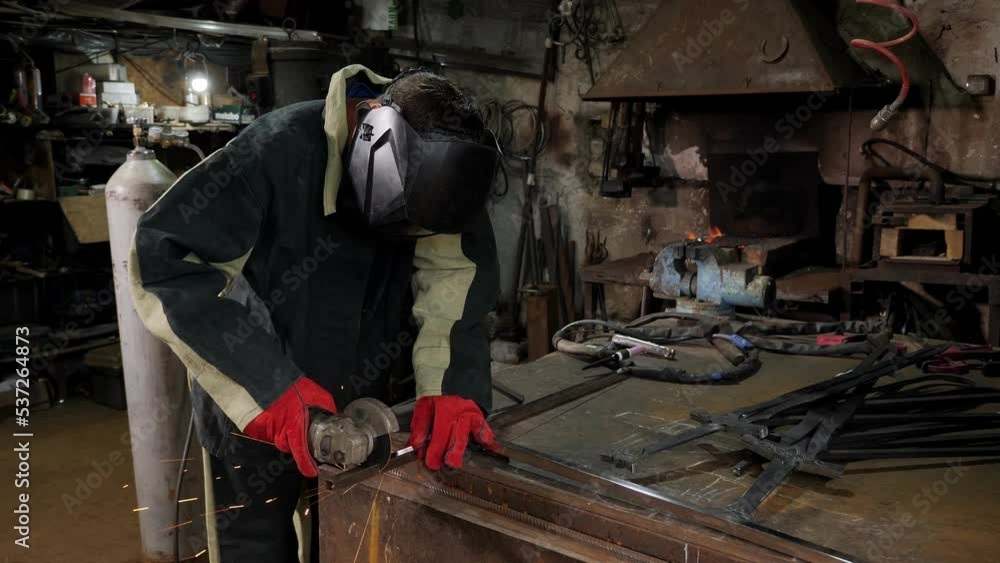 Young manual worker using grinder on metal in factory. Worker grinding in a workshop. Heavy industry factory, metalwork Young manual worker using grinder on metal in factory. Worker grinding in a workshop. Heavy industry factory, metalwork