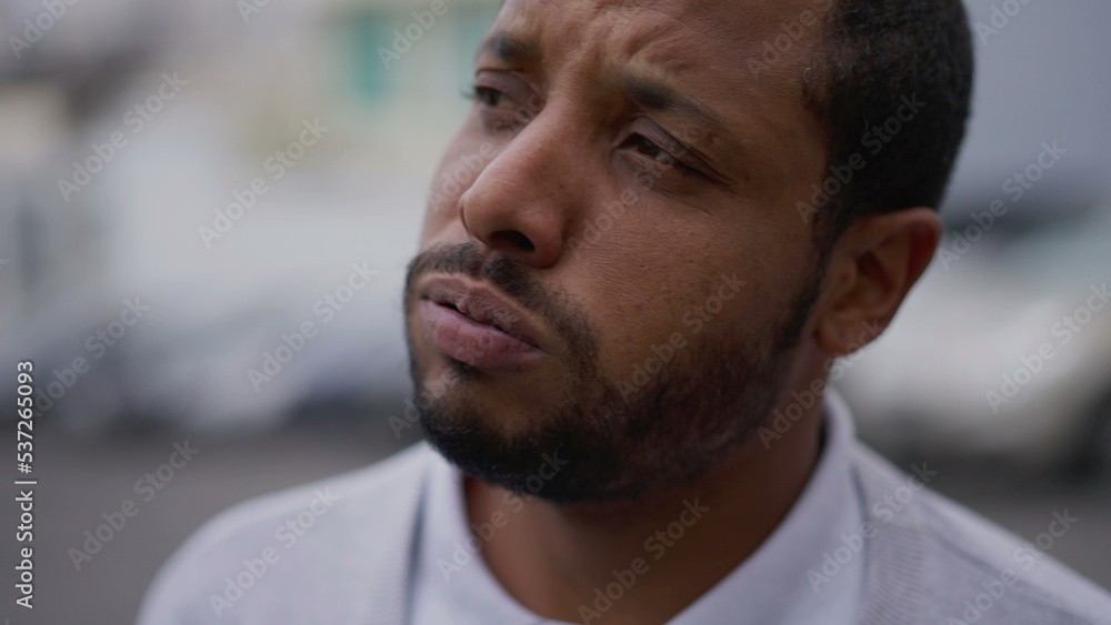 Fototapeta premium One anxious young African American man in distress closeup face. Portrait of a black person with worried preoccupied emotion